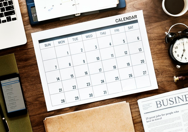 Na psacím stole leží kalendář, notebook a organizér